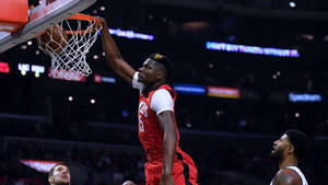 Athlete in red jersey dunks basketball during game with crowd in background. — Clint Background