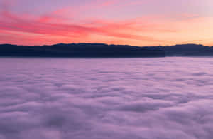 A sea of purple clouds under a pink and orange sunrise with mountain silhouettes. — HD Photography Picture