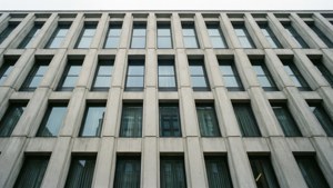 Gray concrete office building with repeating windows and dark curtains. — Concrete Background