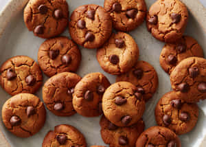 Freshly baked chocolate chip cookies in a speckled ceramic bowl.