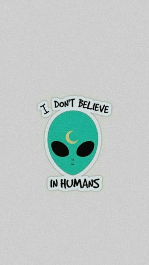 Sticker of a green alien with a moon on its forehead saying I DON'T BELIEVE IN HUMANS.
