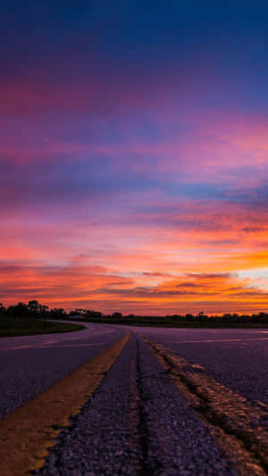Winding road under a colorful sunset sky with orange pink and purple clouds. — Cool Sunset Picture