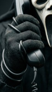 Close-up van Ghostface-hand die telefoonsnoer vastgrijpt, macro-horror
