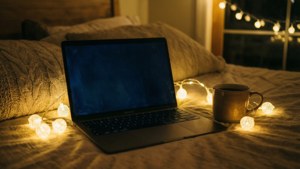 MacBook in einem gemütlichen Raum mit Lichterkette und Kaffee.