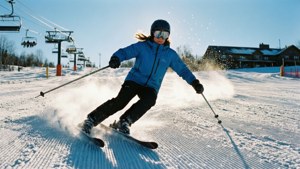 Scherpe bocht op een geprepareerde piste met glinsterende sneeuw en uitzicht op de bergen.