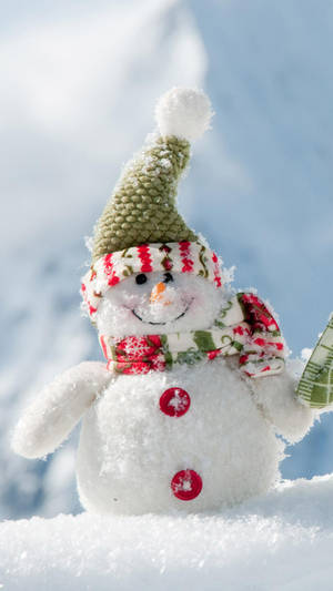 A smiling snowman wearing a green hat and red buttons in a snowy landscape.