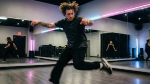 Dynamisk dansövningsbild av Vernon med rörelseoskärpa och neonaccenter.