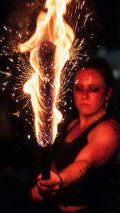 A mesmerizing fire dancer with a spinning staff against a dark backdrop