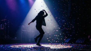 A dramatic silhouette of a dancer on stage with confetti.