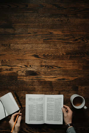 Mãos lendo um livro com lápis e caneca em mesa de madeira — Dark Book Aesthetic Papéis de Parede