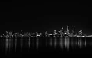Black and white city skyline at night with lights reflecting in water. — Cool Dark Desktop Picture