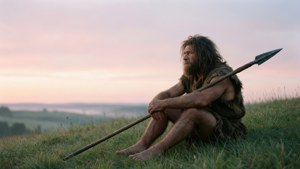 Un uomo delle caverne solitario osserva l'alba da una collina erbosa.