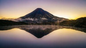 Mount Taranaki speglad i sjön vid soluppgång, gyllen-lila himmel, fridfull alpscen