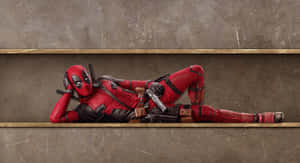 Deadpool reclines on a metal shelf in a worn industrial space. — Deadpool Wallpaper