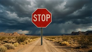Deserto surreale con gigantesco cartello rosso di stop sotto cielo tempestoso