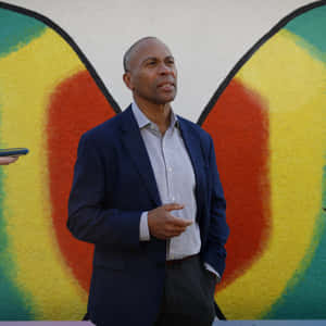 Man in blazer speaking in front of colorful street mural. — Deval Patrick Picture