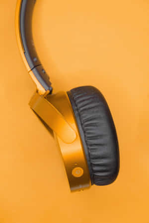 Cuffia over-ear dorata con cuscinetto nero su sfondo arancione — Dispositivo Sfondi