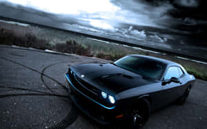 Black muscle car drifting on coastal road under stormy sky