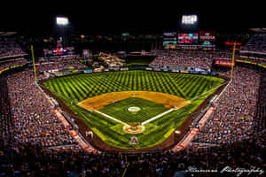 Night baseball game with packed stands and bright stadium lights.