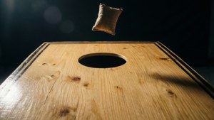 Et dramatisk nærbillede af en bønnesæk på vej mod et cornhole-bræt.