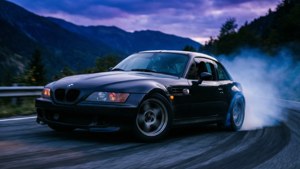 BMW Z3 som kör sladd på en bergsväg med dramatisk belysning.