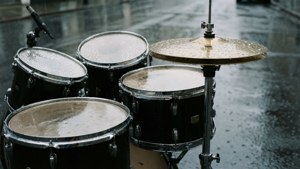 Une batterie laissée sous la pluie, des gouttes d'eau sur les cymbales et les peaux.