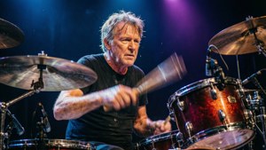 Dynamische lage hoek van Roger Taylor die drums speelt met kleurrijke lichten