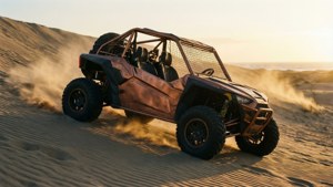 En kobberfarget buggy som klatrer en bratt sanddyne ved soloppgang med støvspor.