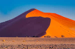 Vast orange sand dune with purple shadow under blue sky in desert — 4K Desert Wallpaper