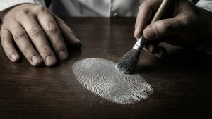 Un drammatico primo piano della polvere per impronte digitali su un tavolo di legno scuro con motivi spettrali