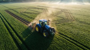 Pemandangan udara abstrak dari traktor New Holland yang membuat pola geometris di ladang hijau saat fajar