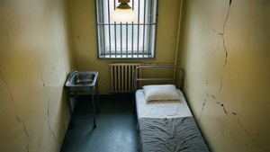 Ovanifrån vy av ett tomt asylpatientrum med gallerfönster och institutionella inventarier