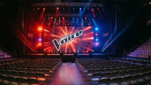 The Voice-logo projisoituna lavan näytöille tyhjässä konserttisalissa.
