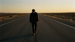 Een eenzame figuur die in angst over een eindeloze snelweg loopt bij zonsondergang