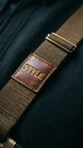 Nahaufnahme eines Hosenträger-Lederpatches mit eingravierter Schrift 'STYLE'.