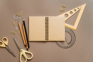 Composition à plat de fournitures scolaires et de bureau sur une surface beige.