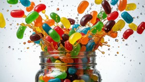 Høyhastighetsbilde av fargerike Android-gelébønner som spruter ut av en krukke med vanndråper.