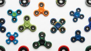 Kumpulan fidget spinner berwarna-warni membentuk pola di atas putih.