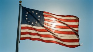 Betsy-Ross-Flagge weht unter einem hellblauen Himmel, patriotisch und lebendig.