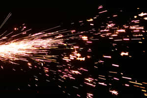 Bright sparks flying in darkness from a welding or cutting process. — Stick Background