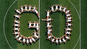Luftaufnahme von Cheerleadern, die das Wort 'GO' auf einem Feld formen.