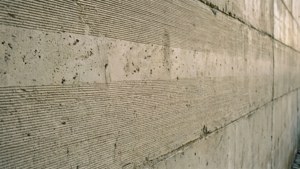 Mur en béton avec empreinte de coffrage en bois, tons chauds.