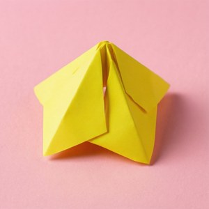 Un post-it jaune plié en forme de diseuse de bonne aventure sur un fond rose.