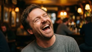 Ricky Gervais gevangen in een volle, vreugdevolle lach in een gezellige pubomgeving