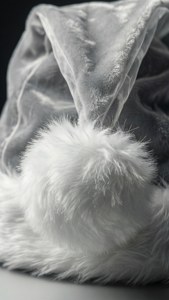 White velvet Santa hat with fluffy pom-pom on dark background