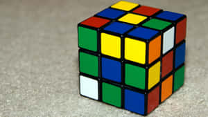 Un cubo de Rubik resuelto descansando sobre una alfombra beige — Fondods de juegos Fondos