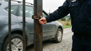 Guarda de segurança abrindo um portão para um carro.