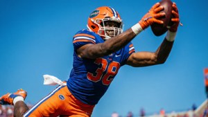 A low-angle action shot of DJ Humphries at Florida, leaping to block a pass.