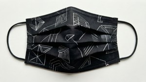 Et fladt billede af en sort stofmaske med geometrisk mønster.