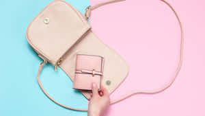 Hand inserting a pink wallet into a pink crossbody bag on a blue and pink background. — Girly Wallpaper
